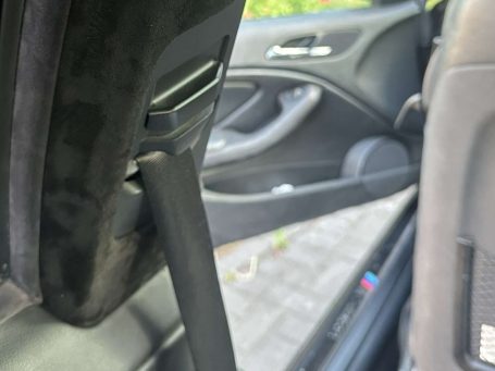 Detailansicht des Innenraums eines Fahrzeugs mit Fokus auf die Türverkleidung. Die Folierung  mit Alcantara der B-Säule ist zu sehen.